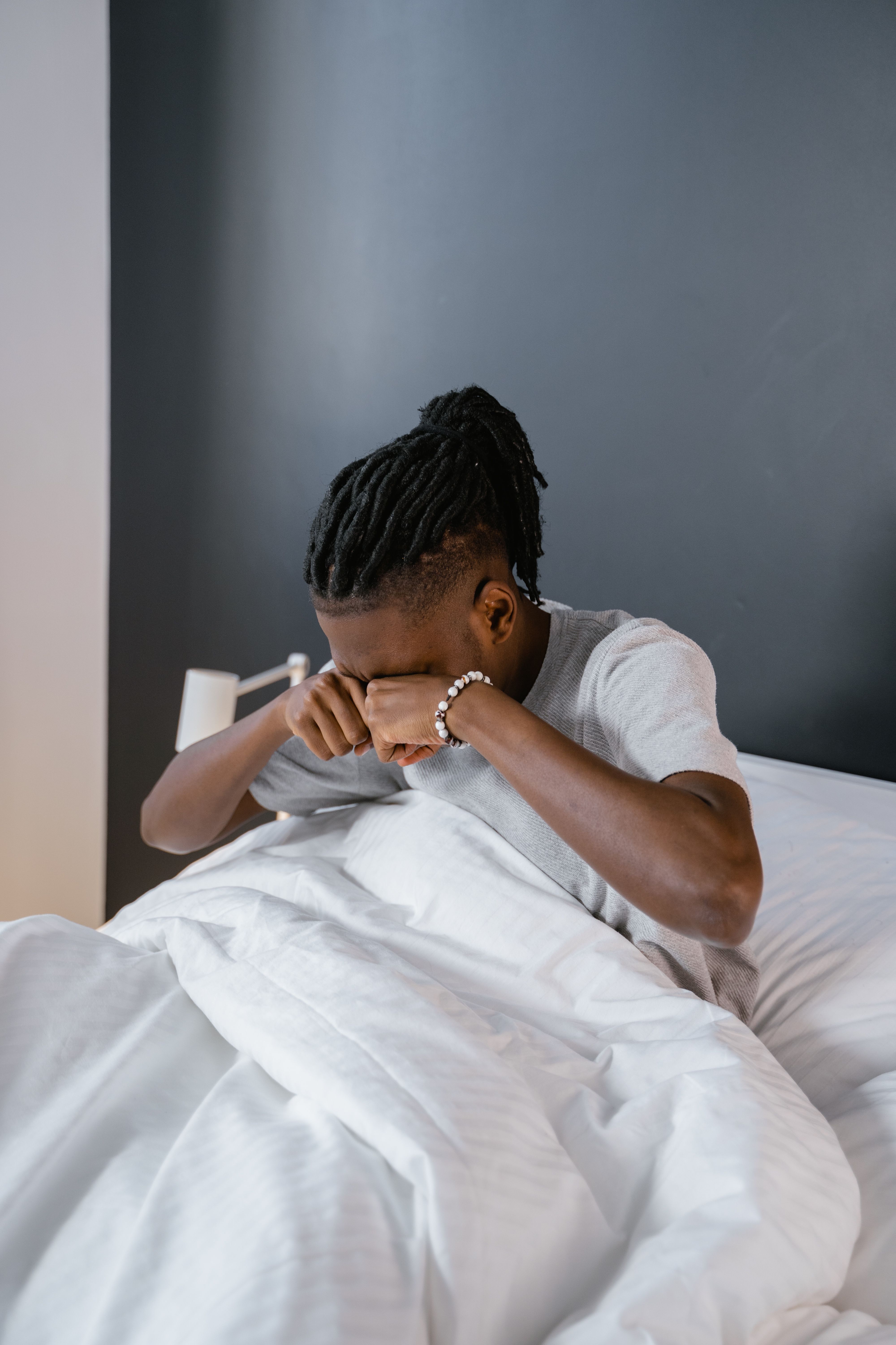 Homem sentado na cama, esfregando os olhos; foto ilustrativa.